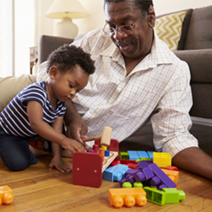 Financial Tips for New Grandparents Grandfather and grandson playing on the floor